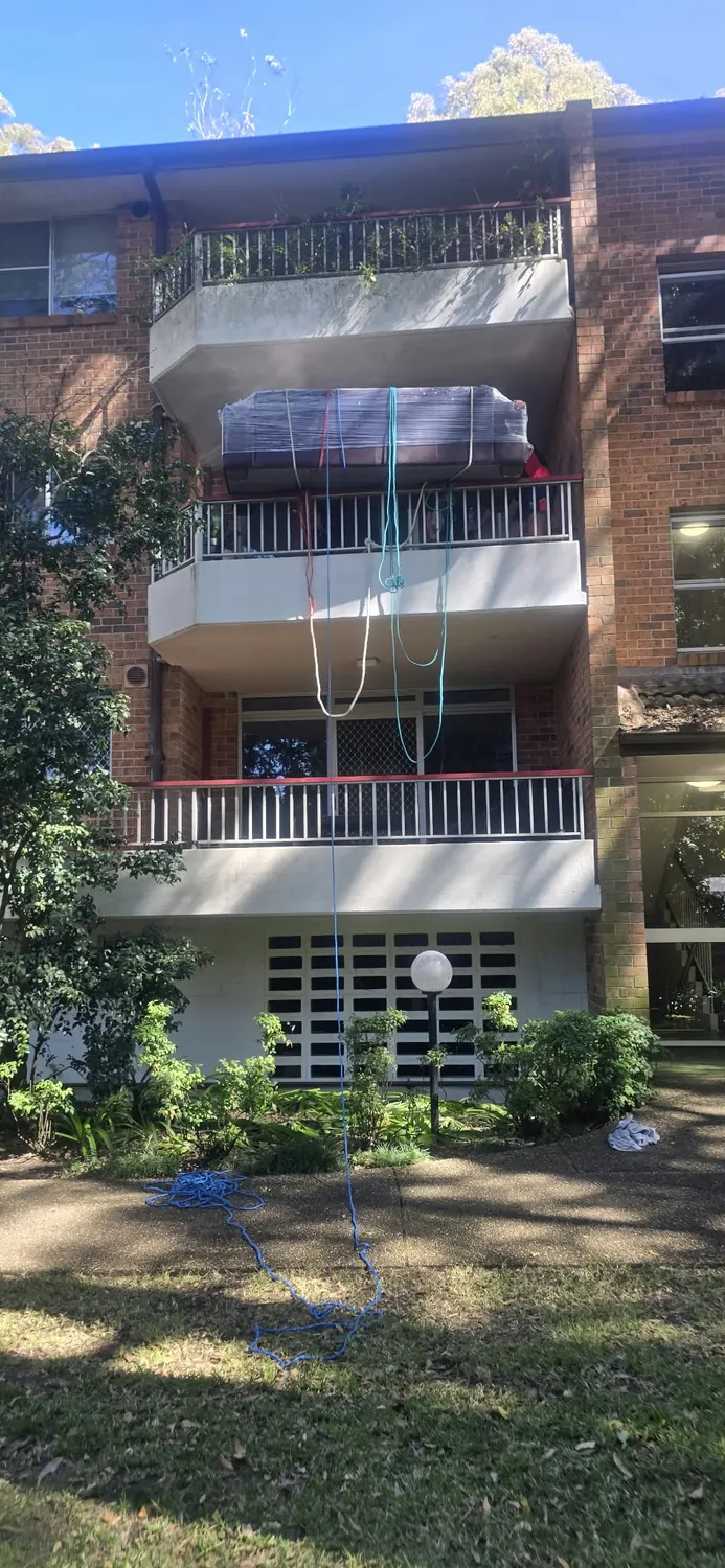 Wrapped lounge lifted over a balcony railing during a Hornsby unit move