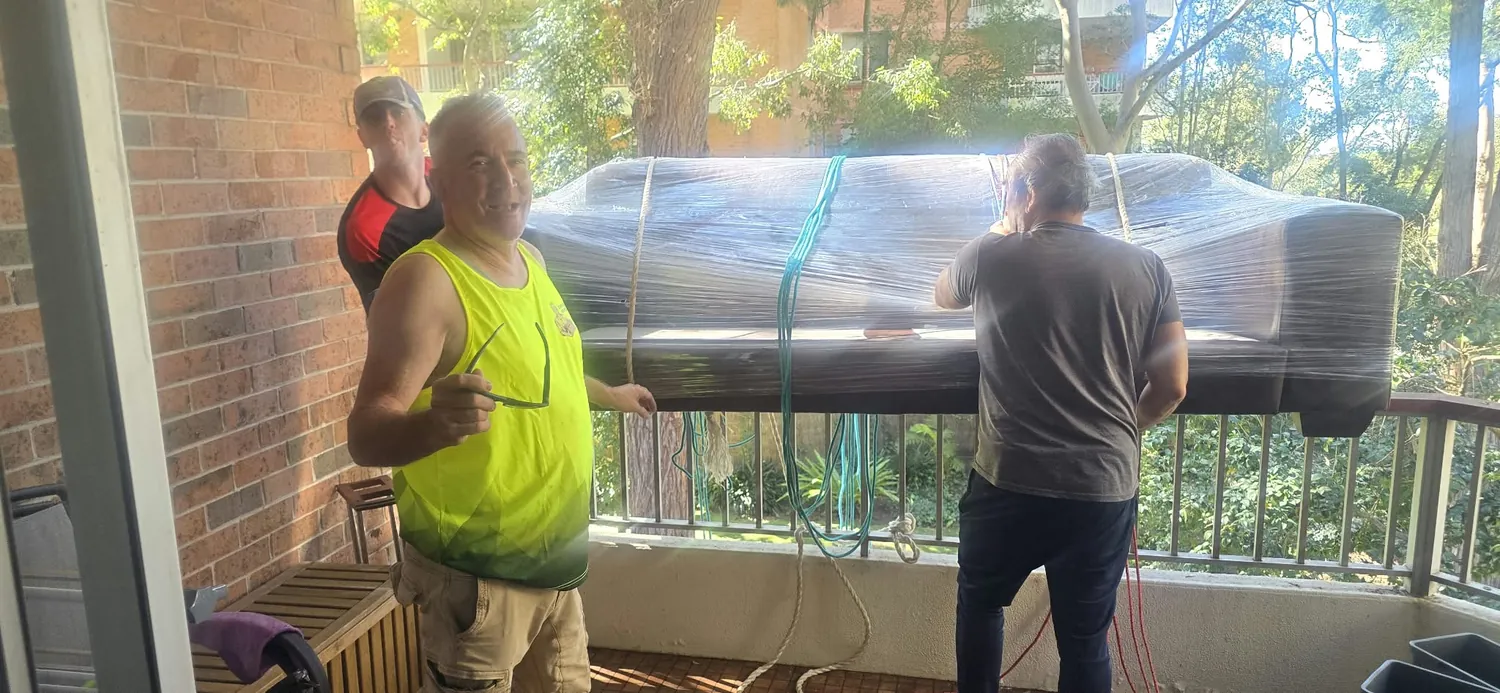 Careful Movers crew with a plastic wrapped lounge on a Hornsby balcony
